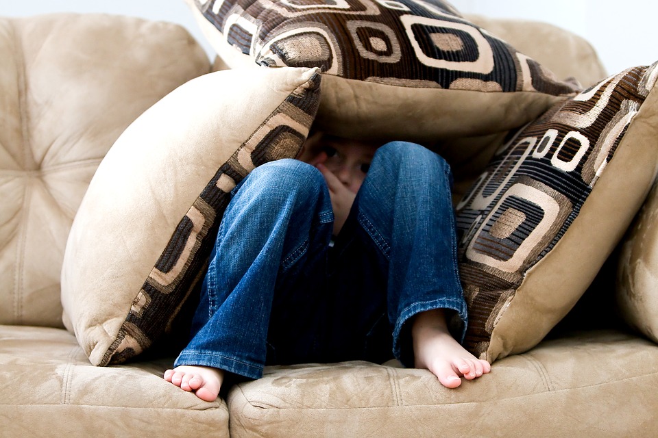 мальчик с подушками сидит на диване