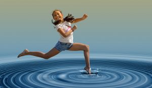 счастливая девочка прыгает по воде
