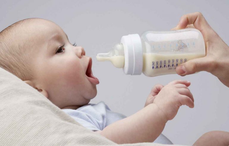 ребенок пьет молоко из бутылочки