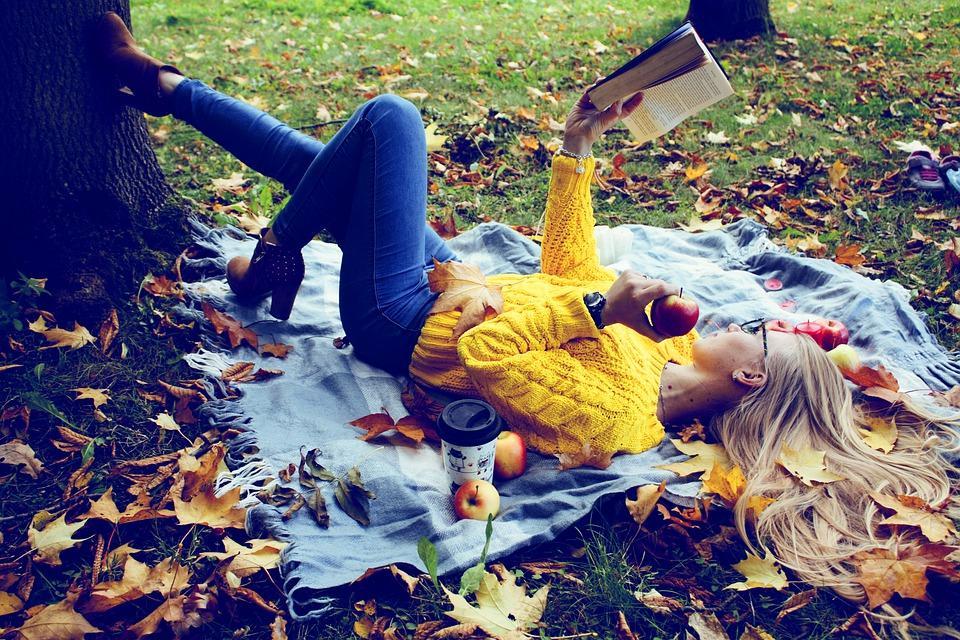 девушка в осеннем парке на ковре из листьев с книгой