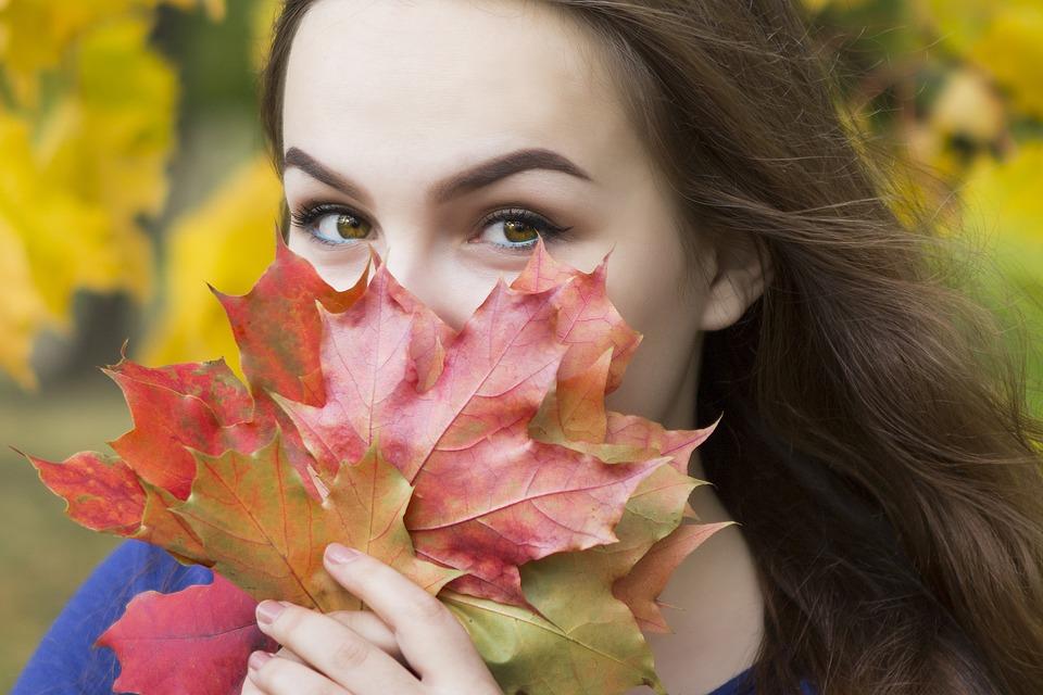 листья клена осенью у лица женщины 